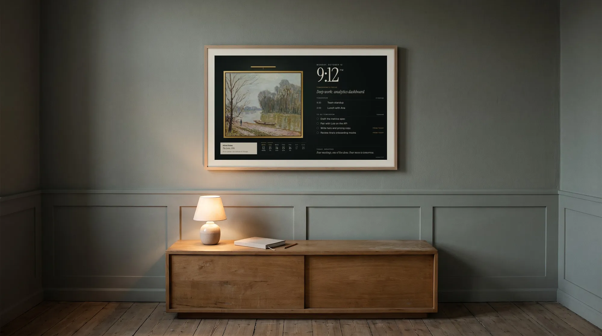 A quiet room at night with a Samsung Frame on the wall showing Frame Dashboard: a painting in a gilt frame beside tomorrow’s plan